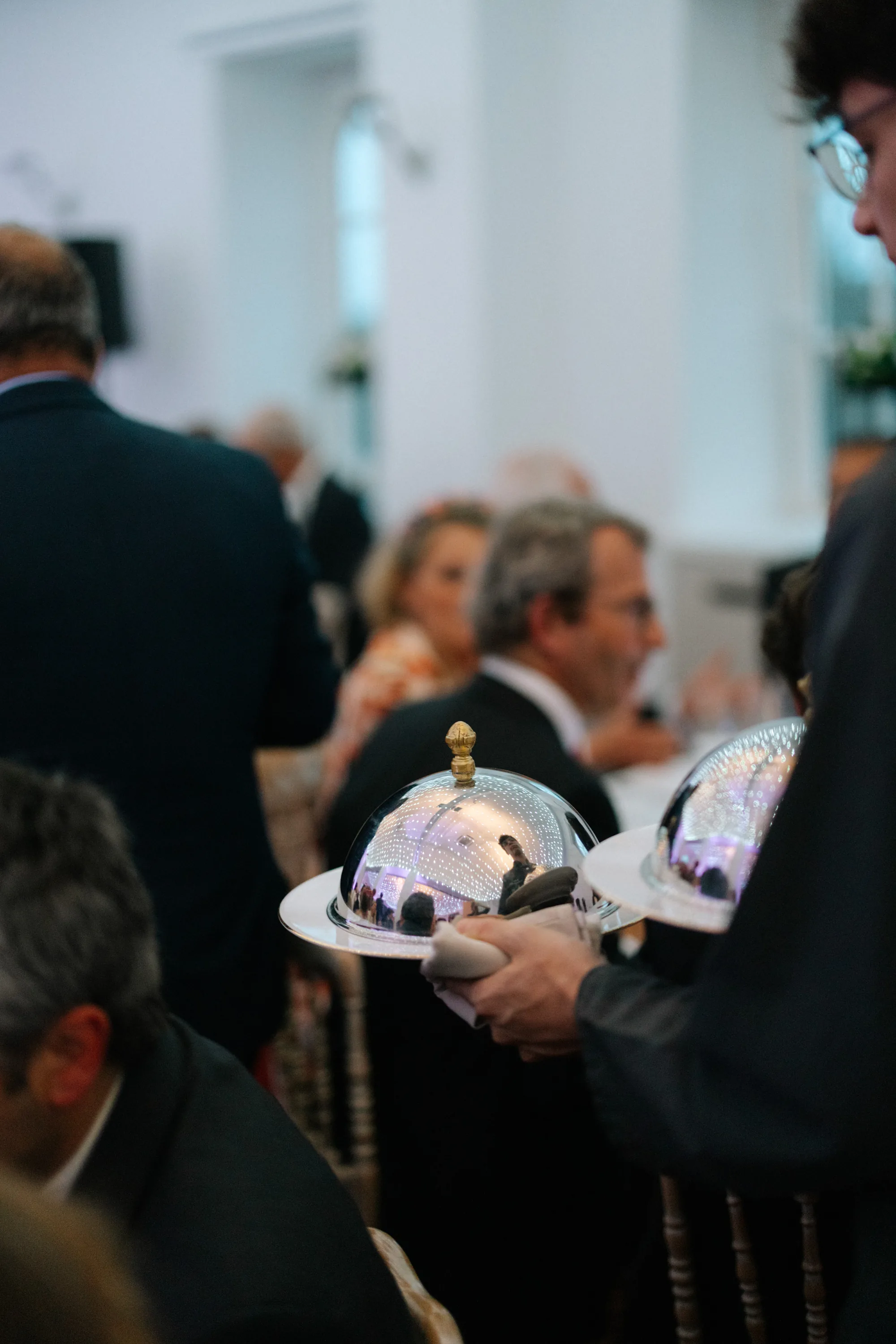 Mariée tenant un bouquet de fleurs blanches, invités flous en arrière-plan