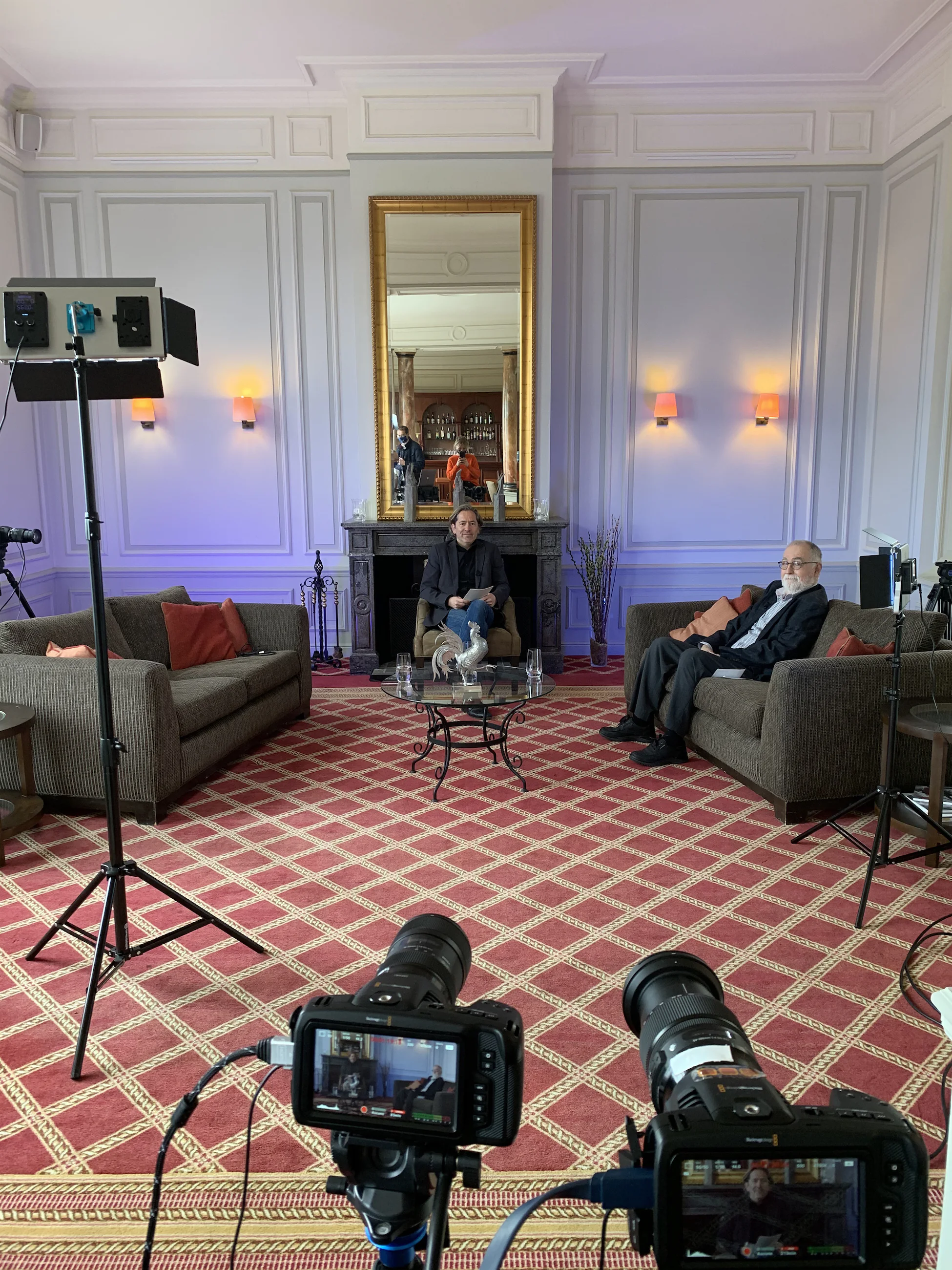 Deux canapés se faisant face avec équipement de tournage et éclairage dans un salon