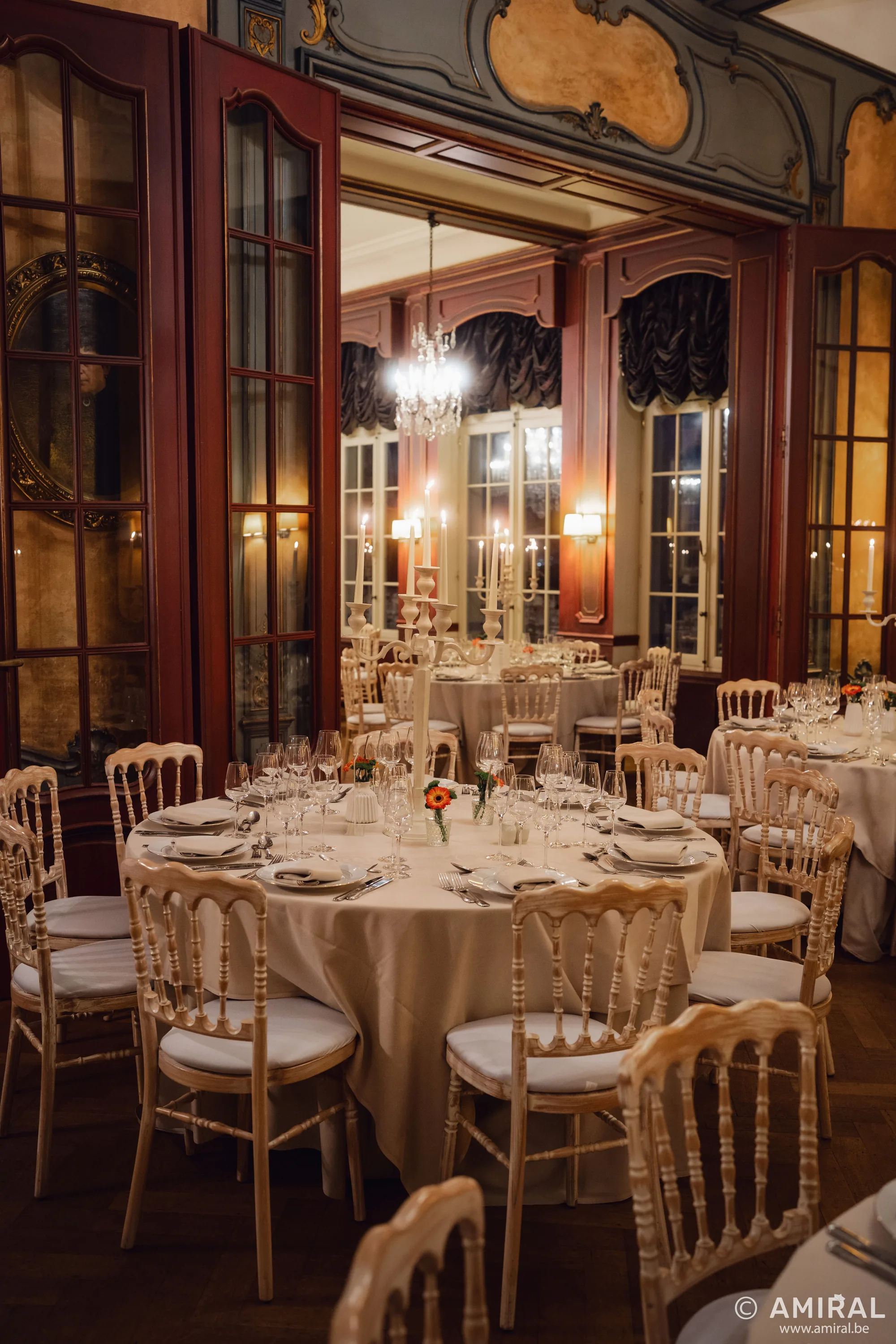 Salle de réception élégante avec tables dressées, chaises dorées et boiseries sombres