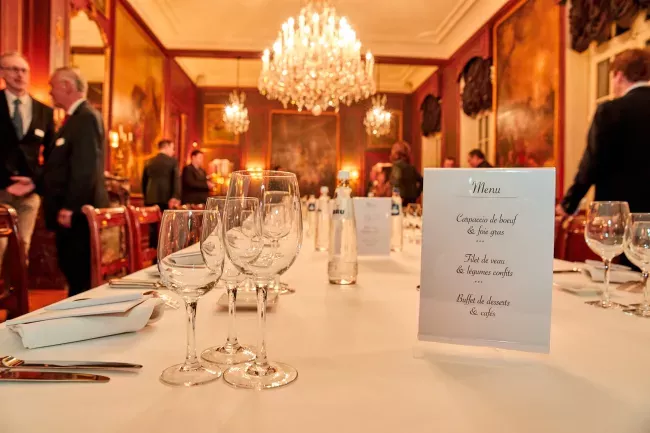 Salle de banquet élégante avec lustre, tables dressées et invités en arrière-plan