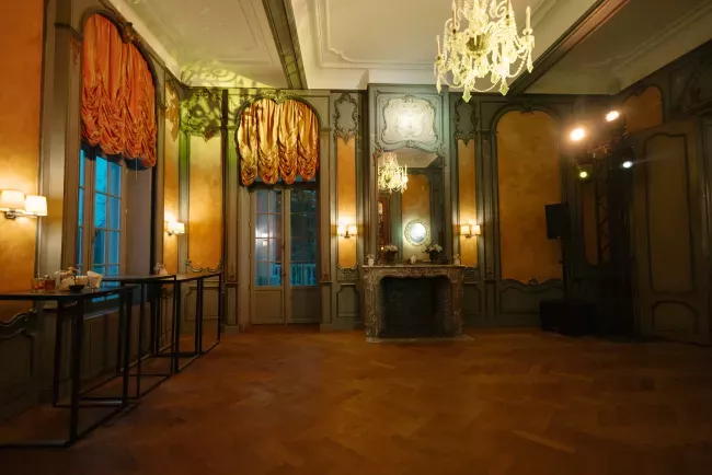 Salle de réception élégante avec parquet, lustres et murs ornés de tapisseries.