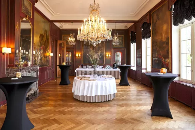 Salle de réception élégante avec lustres, boiseries et tables cocktail drapées de noir