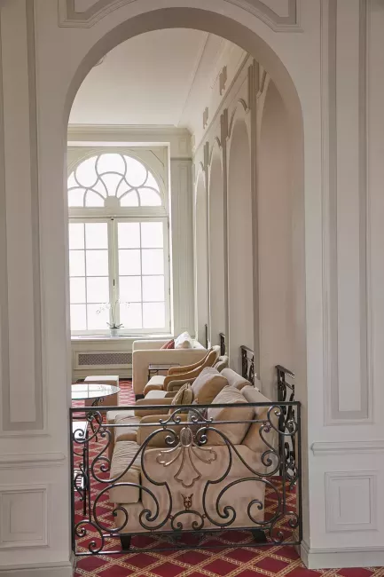 Couloir élégant avec arche blanche, garde-corps en fer forgé et fenêtre lumineuse