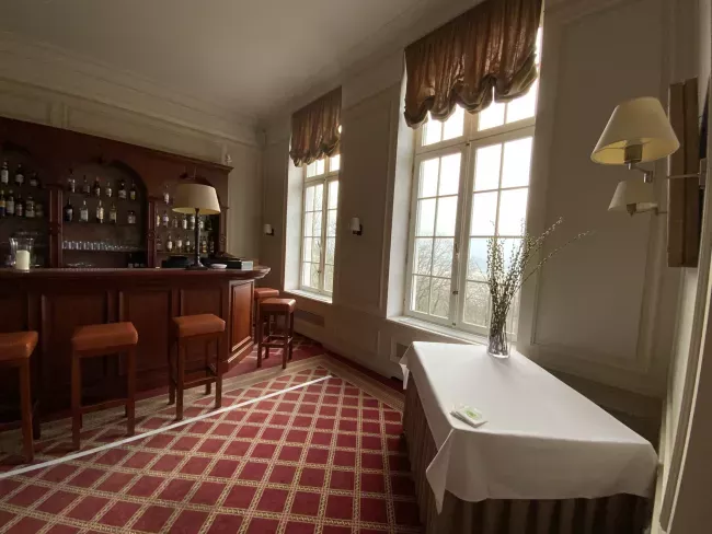 Salle à manger avec bar en bois, moquette à carreaux rouges et grandes fenêtres lumineuses