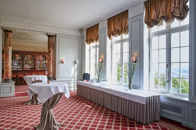 Salle à manger élégante avec sol en damier rouge et blanc, grandes fenêtres et rideaux dorés