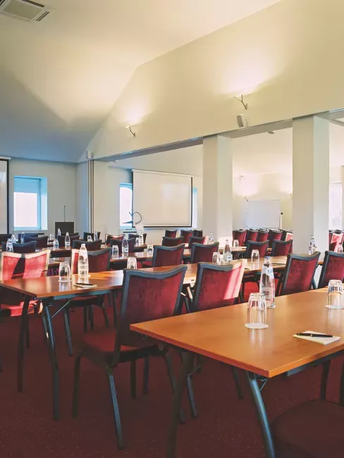 Salle de réunion avec tables en bois et chaises violettes, grandes fenêtres lumineuses
