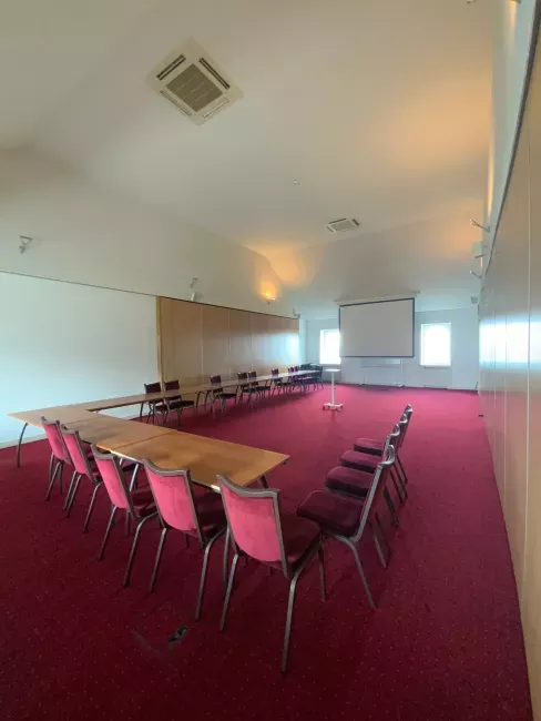 Salle de réunion avec grande table rectangulaire recouverte de tissu rouge et chaises alignées